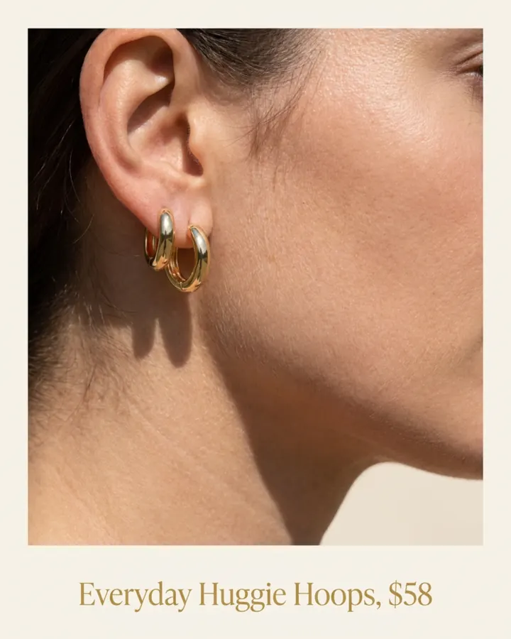 AI output for the fifth prompt: a close-up of one ear and jawline wearing both chunky gold hoops in the same lobe, overlapping, inside a frame with Everyday Huggie Hoops, $58 written below.