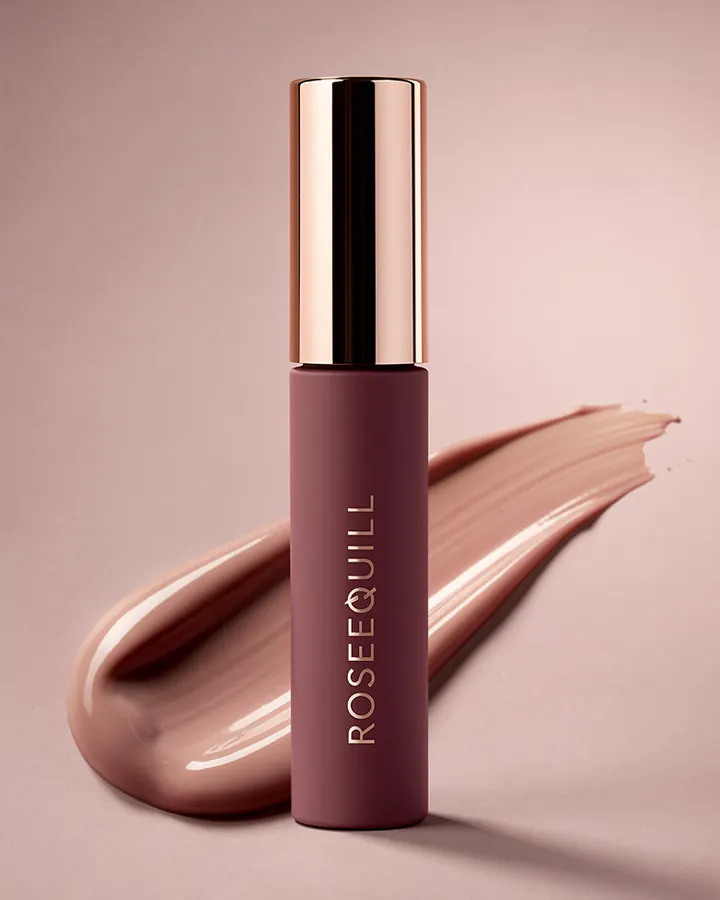 AI output for the third prompt: a plum tube with a rose gold cap and vertical lettering that reads Roseequill, in front of a glossy beige smear on a dusty pink background.