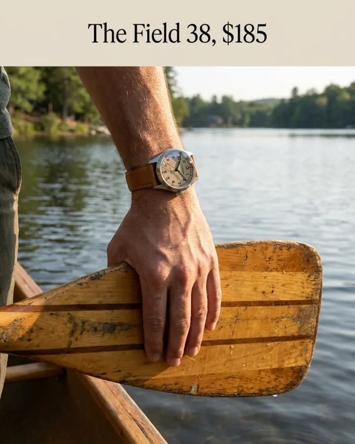 AI output for the fifth prompt: a man's hand on a wooden canoe paddle by a lake, a small field watch on his wrist with the dial too small to read, under the line The Field 38, $185.