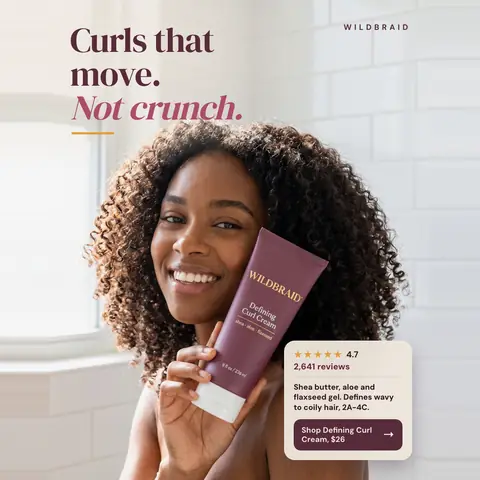 Soft white tiled bathroom look, Wildbraid ad: 'Curls that move. Not crunch.' A smiling woman with voluminous curly hair holds a plum Defining Curl Cream tube to her cheek. A card shows 4.7 stars, 2,641 reviews, and a 'Shop Defining Curl Cream, $26' button. The 1:1 version.