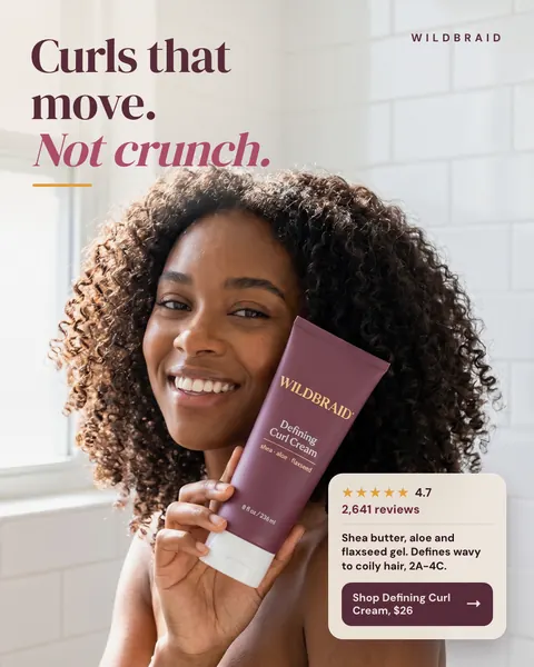 Soft white tiled bathroom look, Wildbraid ad: 'Curls that move. Not crunch.' A smiling woman with voluminous curly hair holds a plum Defining Curl Cream tube to her cheek. A card shows 4.7 stars, 2,641 reviews, and a 'Shop Defining Curl Cream, $26' button. The 4:5 version.